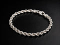 A silver twisted rope chain bracelet with a lobster clasp, displayed on a dark black background.