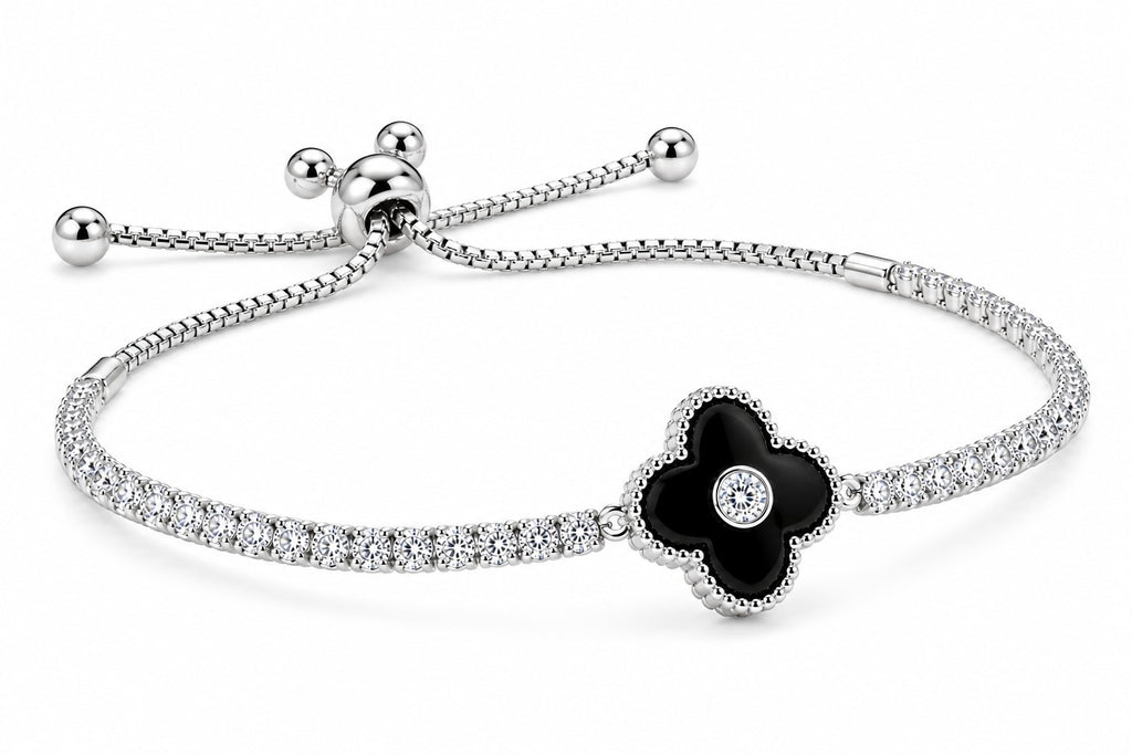 A silver-toned bracelet featuring a four-petal flower centerpiece with a black enamel center and a small clear stone, set on a pavé-set silver band with an adjustable sliding closure.