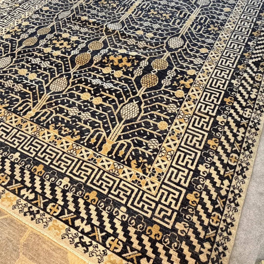 Close-up of a black and cream Afghan Khotan wool rug showing its woven pattern and product label.
