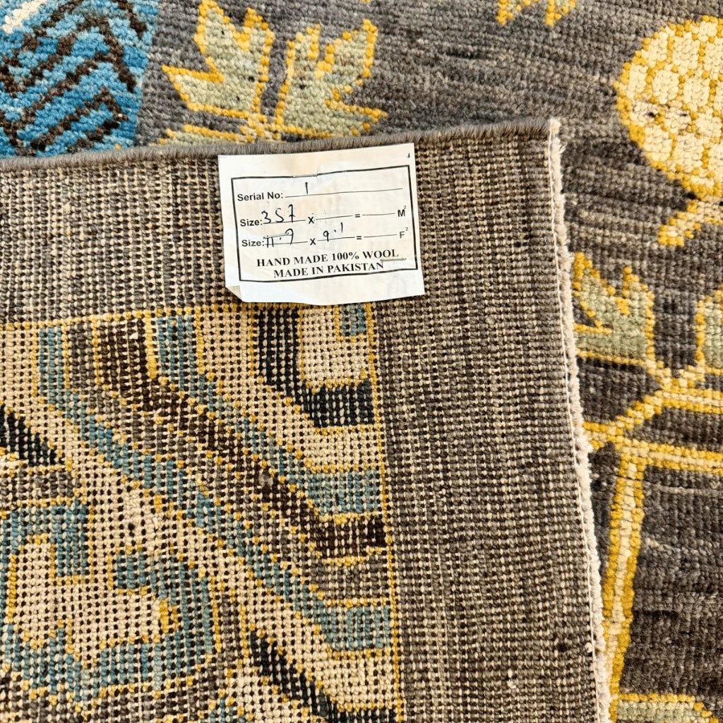 Fringed edge of a traditional Afghan Khotan wool rug with a charcoal grey field and decorative border.