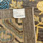 Fringed edge of a traditional Afghan Khotan wool rug with a charcoal grey field and decorative border.