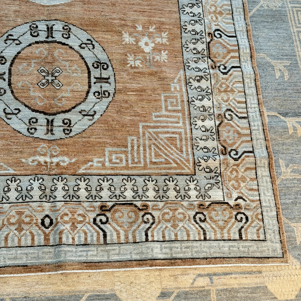 Close-up of the Afghan Khotan rug's cream and beige geometric border with dark brown decorative patterns.