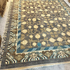 Traditional Afghan Khotan rug featuring repeating cream pomegranate tree motifs on a charcoal grey wool field.