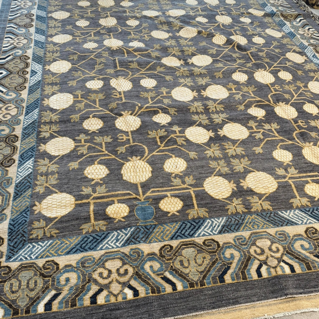 Close-up of the dense wool pile and intricate pomegranate pattern on a charcoal grey Afghan rug.