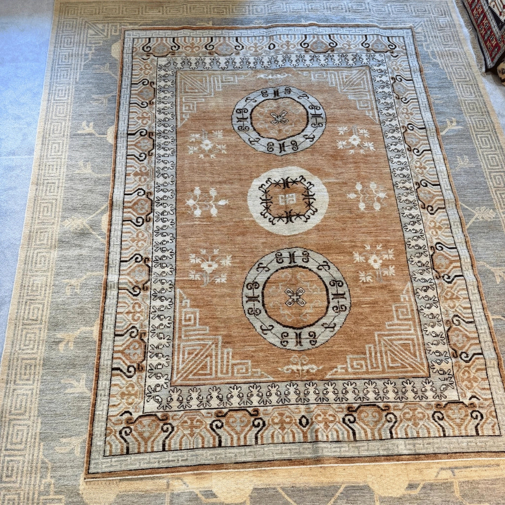 Detailed view of a traditional medallion motif on a tan and light blue Afghan Khotan-inspired wool rug.