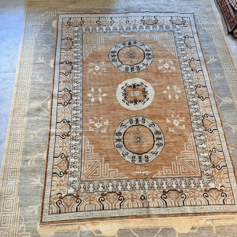 Detailed view of a traditional medallion motif on a tan and light blue Afghan Khotan-inspired wool rug.