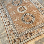 Intricate cream and beige rug border featuring dark geometric motifs on a traditional Afghan-inspired wool area rug.