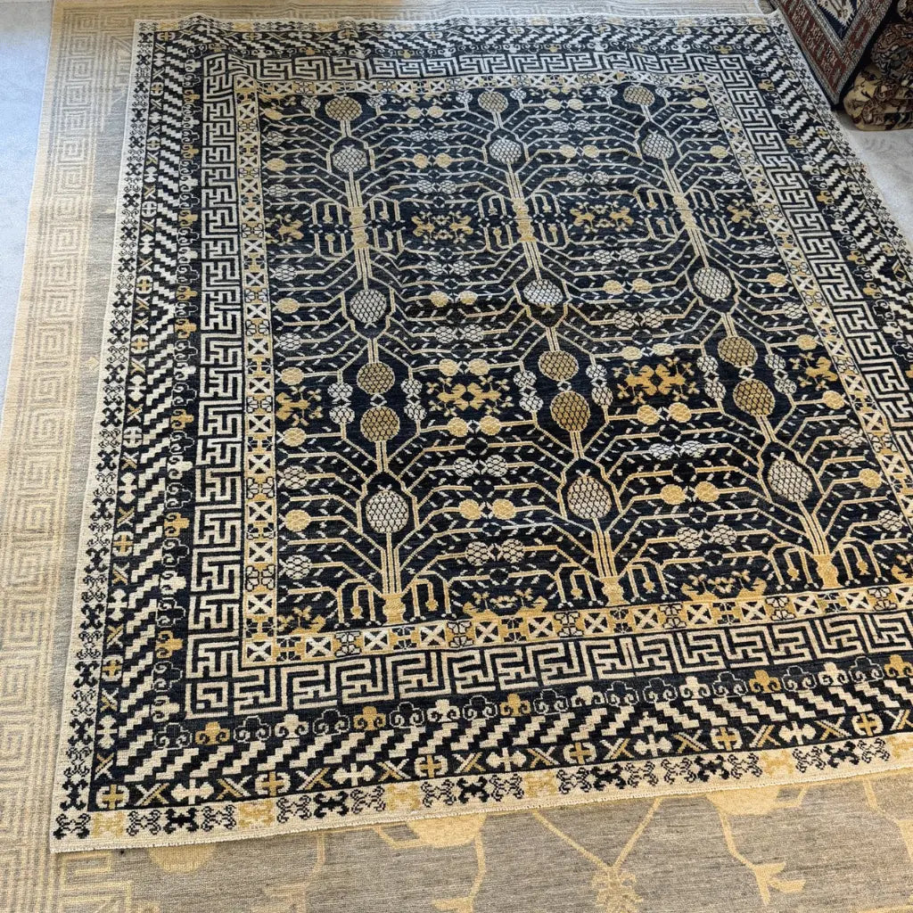 Black Afghan handknotted Khotan wool rug with cream geometric borders and a traditional Tree of Life pattern.