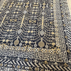 Angled view of a black and cream Afghan Khotan handmade wool rug with intricate traditional geometric patterns.