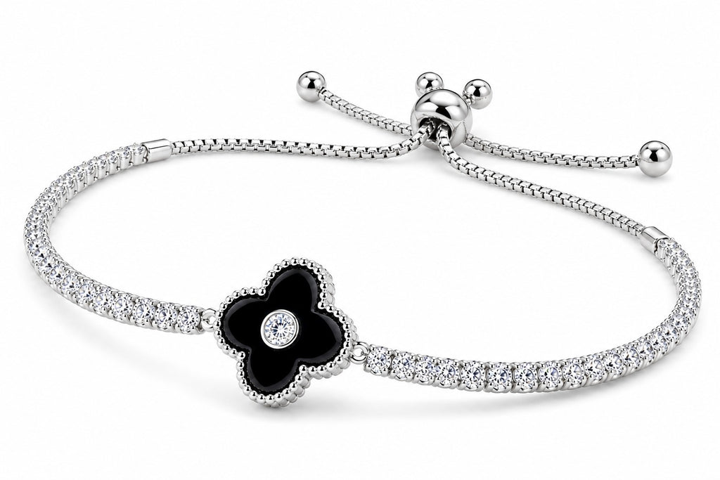 A silver-toned adjustable bracelet featuring a black enamel flower charm with a small clear stone in the center, set against a plain white background.