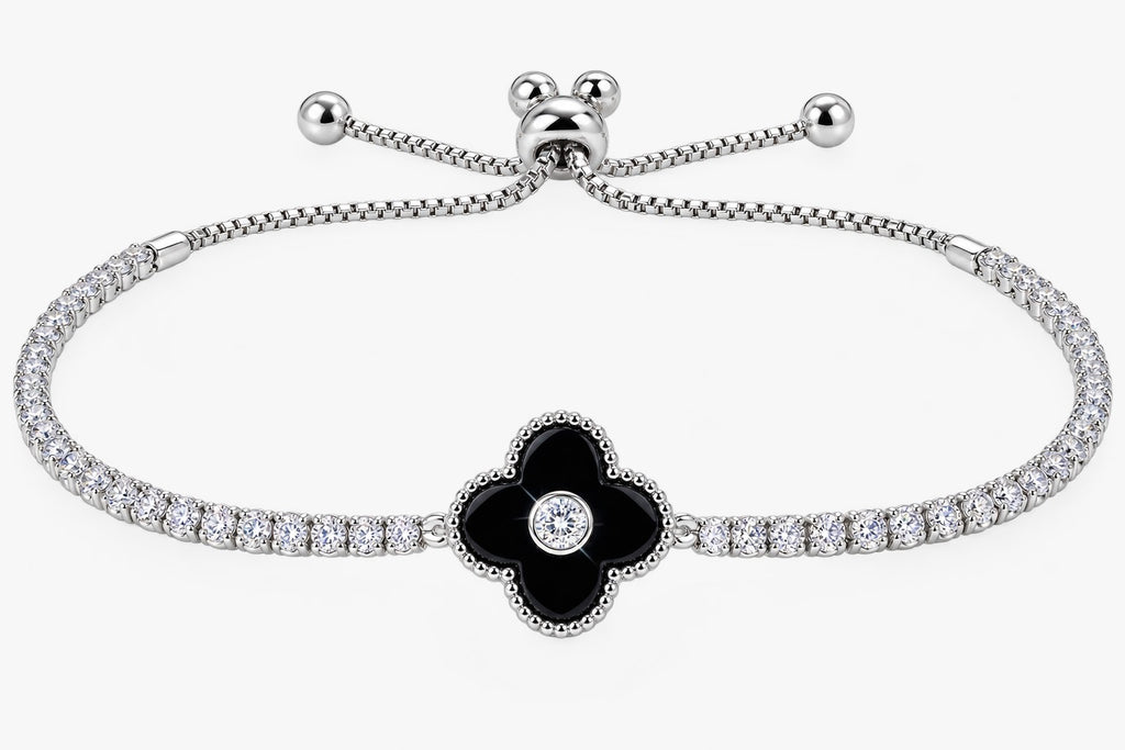 A silver-toned bracelet featuring a central black enamel four-petal flower with a small clear stone in the center, flanked by rows of small clear stones along the chain, on a light gray background.