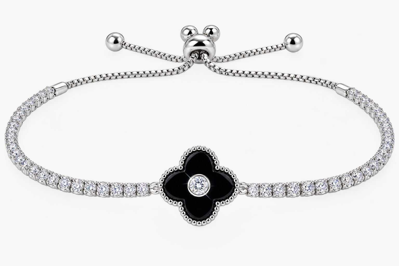 A silver-toned bracelet featuring a central black enamel four-petal flower with a small clear stone in the center, flanked by rows of small clear stones along the chain, on a light gray background.