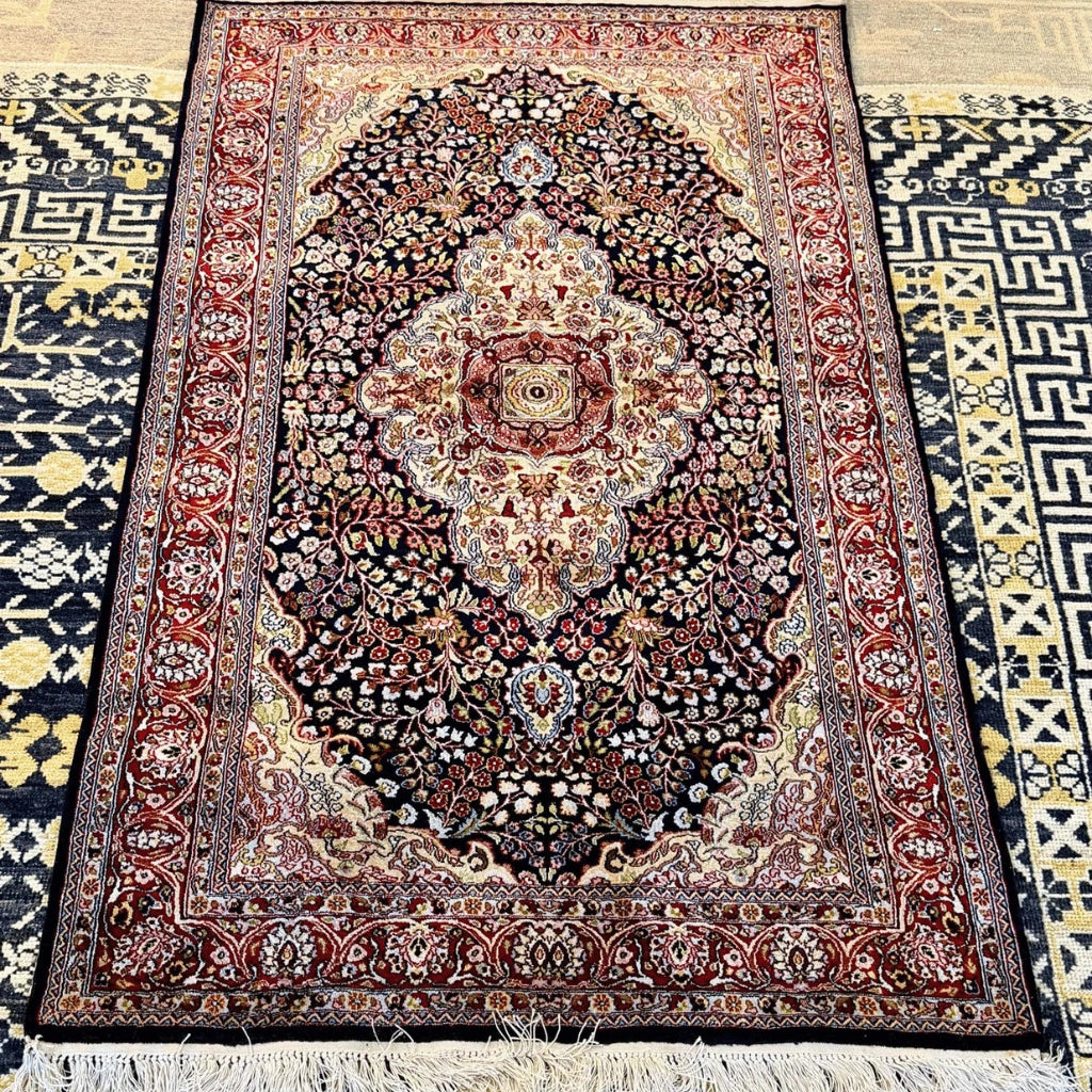 Cream-colored fringe and detailed woven edge of a traditional navy blue Kashmiri silk rug.