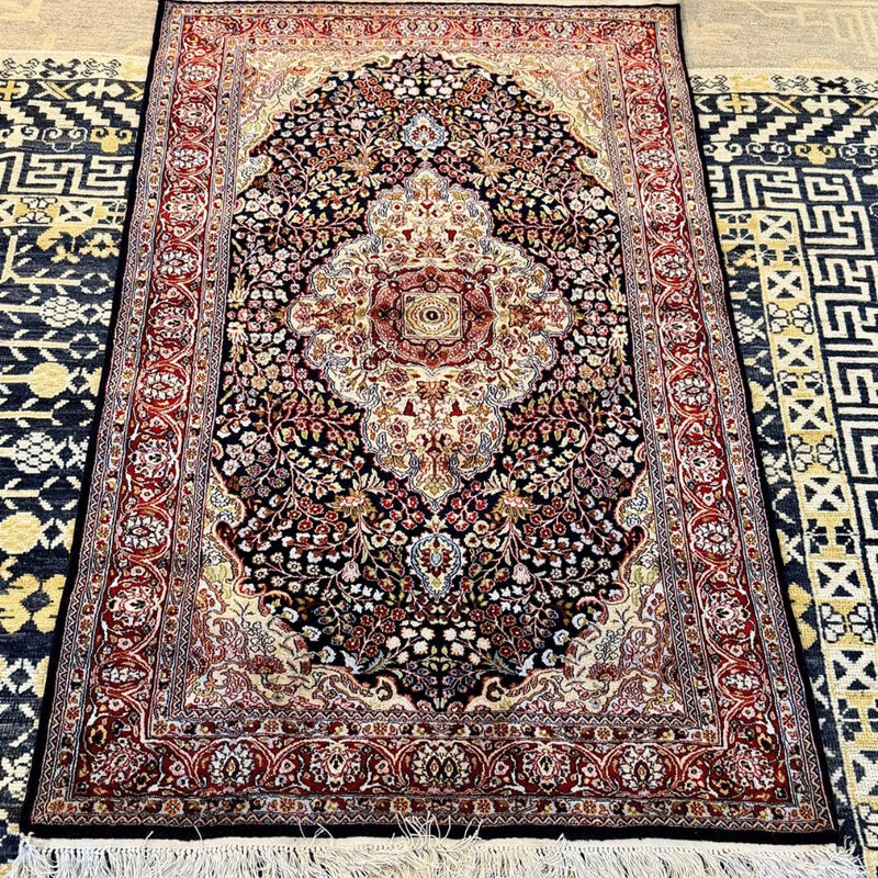 Cream-colored fringe and detailed woven edge of a traditional navy blue Kashmiri silk rug.