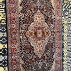 Close-up of the intricate cream and red central medallion with detailed floral motifs on a navy Kashmiri silk rug.