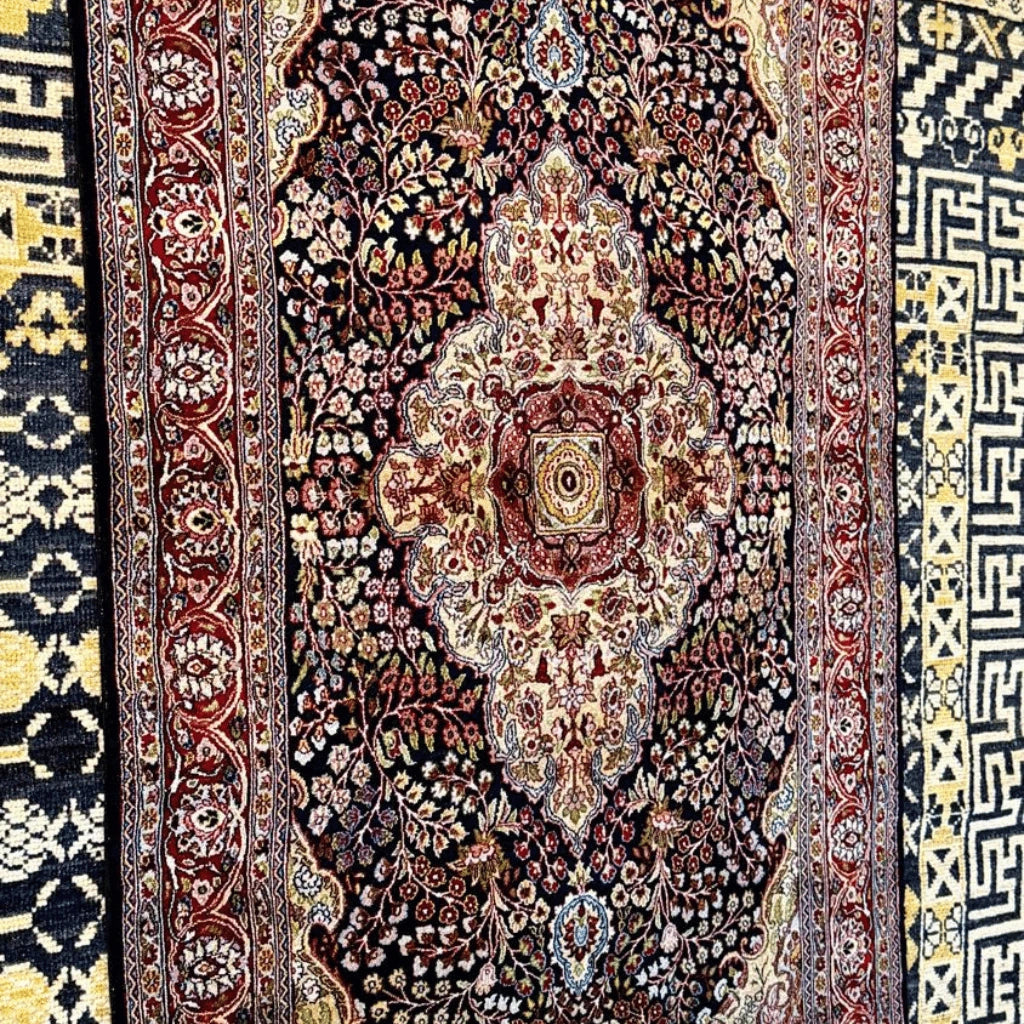 Close-up of the intricate cream and red central medallion with detailed floral motifs on a navy Kashmiri silk rug.