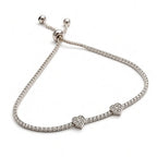 Silver pavé heart charm bracelet with thin tennis band and slider clasp, angled view