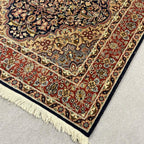 Close-up of rust red floral border and detailed traditional pattern on vintage Persian rug