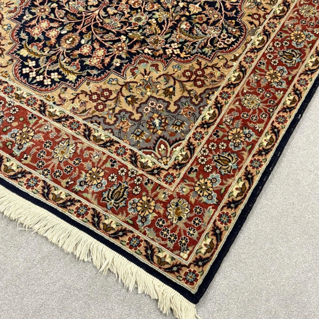 Close-up of rust red floral border and detailed traditional pattern on vintage Persian rug