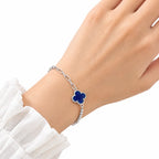 Woman wearing sterling silver blue clover charm bracelet with paperclip chain and beaded detail on wrist with white sleeve