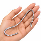 Woman holding silver cubic zirconia tennis bracelet in her palm showing size, clasp and 925 tag