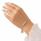 Woman wearing dainty sterling silver adjustable bar bracelet with sparkling cubic zirconia bar on wrist with white ruffle sleeve