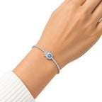 Woman wearing silver hamsa hand evil eye tennis bracelet with cubic zirconia on wrist with white knit sleeve