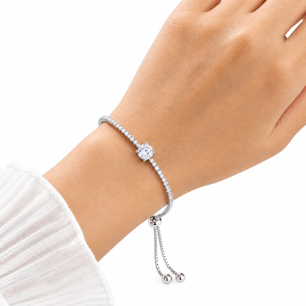 Woman wearing adjustable sterling silver solitaire tennis bracelet with sparkling round cubic zirconia on wrist with white sleeve
